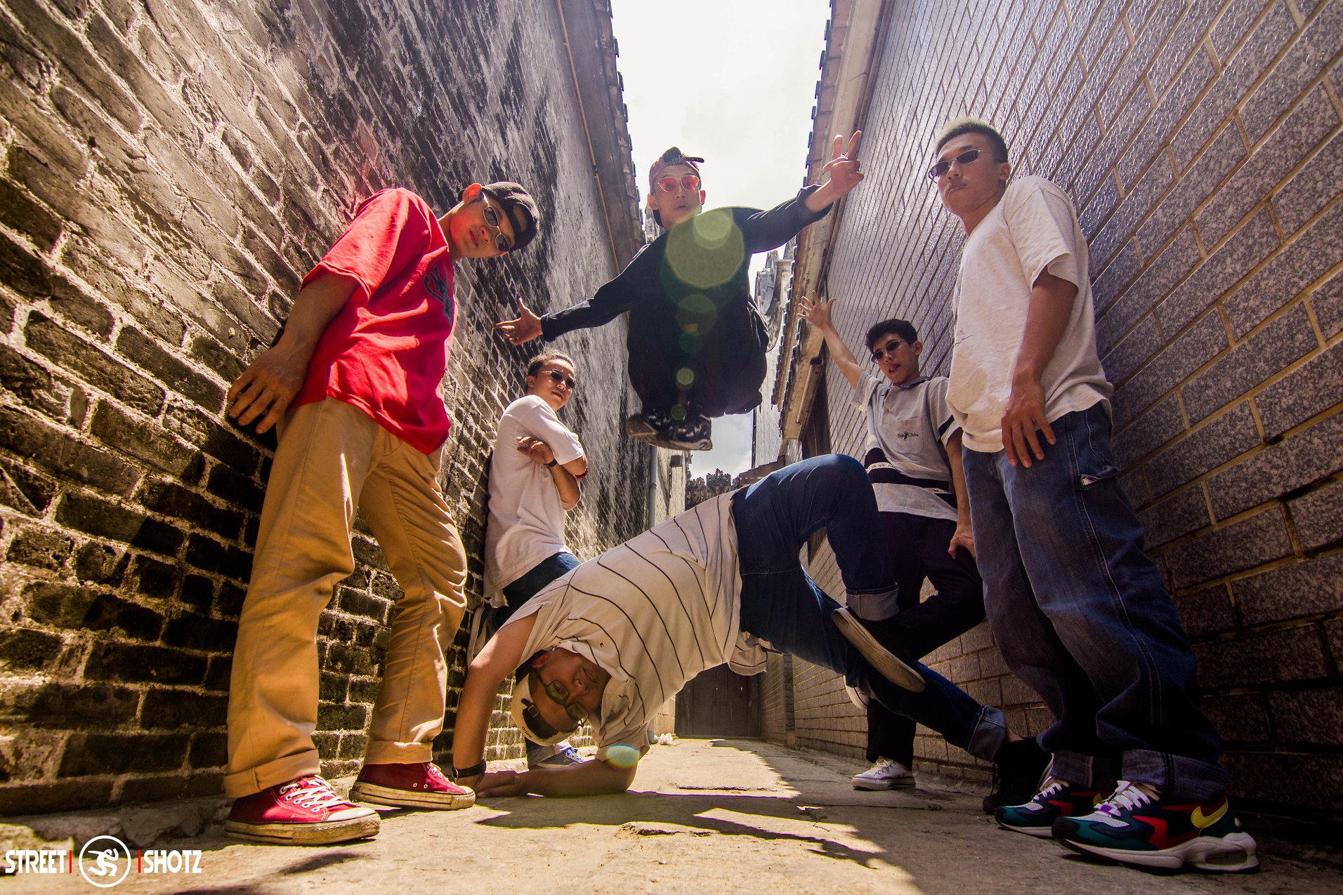 Breaking crew posing in a narrow alleyway between brick walls