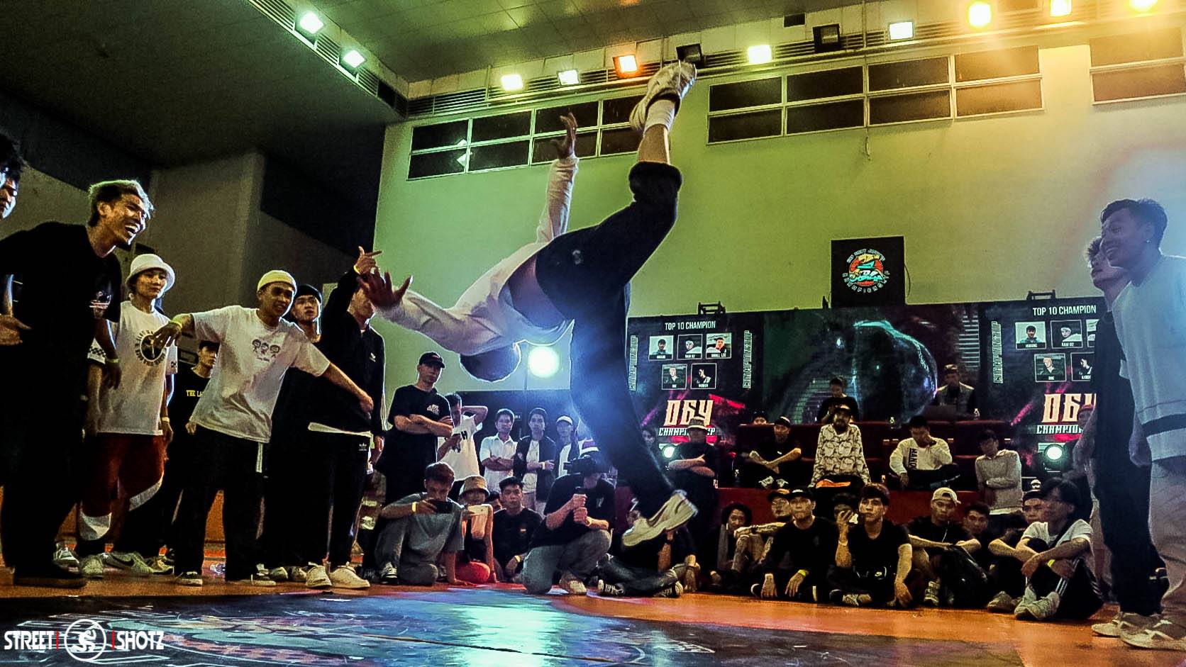 B-boy throwing a power move at a breaking competition with crowd watching